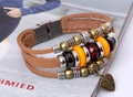 Dettaglio di bracciale multistrato in pelle marrone con perline e ciondolo a cuore - Cuoio