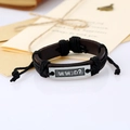 Dettaglio del bracciale in pelle intrecciata a mano con piastra in argento incisa e cordino - Nero