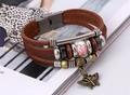 Detail eines mehrlagigen Lederarmbands mit Keramikperle und bronzenem Schmetterlingsanhänger - Dunkelbraun