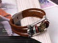 Makro-Detail von dreilagigem braunem Lederarmband mit Bronzekreuz und Metallverschluss - Dunkelbraun