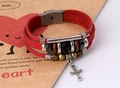 Macro shot of punk leather bracelet with cross pendant and multi-layer bead detailing - Red