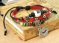 Close-up of retro leather beaded bracelet featuring lip charm on vintage book - Red