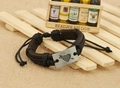 Close-up of retro leather bracelet with heart arrow metal plate on wooden background - Black