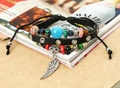 Detail eines Lederarmbands mit Perlen aus Holz und silbernem Flügel-Anhänger - Schwarz