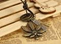 Makro-Detail von Vintage-Ahornblatt und Kreuzanhänger an einer Lederkordel-Halskette - Antikbronze