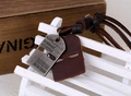 Close-up of vintage engraved metal plate and brown leather tag on adjustable necklace - Antique Silver