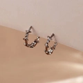 Boucles d'oreilles créoles épines argentées avec design punk sur carte beige - Noir
