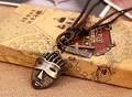 Macro detail of vintage bronze mask pendant with cross on brown leather necklace - Pharaoh Head