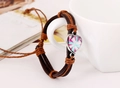 Detail of woven leather bracelet with heart pendant hanging on white ceramic cup - Light Brown Line (Geometric Star)