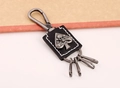 Nahaufnahme eines Punk-Leder-Schlüsselanhängers mit silbernem Totenkopf-Relief und Karabiner - Schwarz