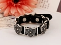Dettaglio del bracciale punk in pelle vintage con fibbie a scudo incise con motivi a croce - Nero