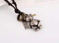 Detailed close-up of retro teddy bear pendant and engraved plate on a leather necklace - Cartoon Bear