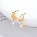 Orecchini in argento dorato con zirconi a goccia esposti su ceramica bianca elegante - Argento 925 / Oro
