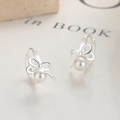 Elegantes pendientes de lazo en plata 925 con perlas blancas sobre fondo de libro - Plata 925 / Plateado