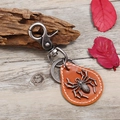 Vintage punk leather keychain featuring a silver spider charm on a rustic wood background - Tan