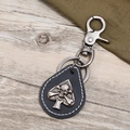 Close-up of black spade leather keychain with silver skull emblem and lobster clasp - Black