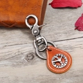 Macro detail of vintage leather keychain with peace sign and antique metal clasp - Tan