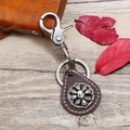 Vintage Leder-Schlüsselanhänger mit Totenkopf-Emblem auf hellem Holzhintergrund - Dunkelbraun Totenkopf