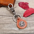Vintage-Adler-Emblem Leder-Schlüsselanhänger mit Retro-Metallkarabiner auf Holzgrund - Hellbraun Adler