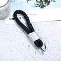 Detail of hand-woven black leather keychain with polished silver metal ring on white stone - Silver Tone + Black Rope