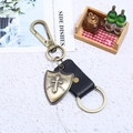 Retro genuine leather keychain with bronze shield cross charm on a white stone background - Black