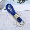 Detailaufnahme von blauem Leder-Schlüsselanhänger mit goldener Halterung auf Tisch - Bronze + Blaues Seil