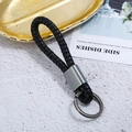 Detail of black woven leather keychain with dark gray metal ring on decorative tray - Antique Silver + Black Rope