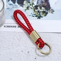 Close-up of red and black braided leather keychain with vintage bronze metal ring - Bronze Tone + Red Black Rope