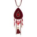 Detailed macro view of bohemian drop necklace featuring red fringe and gold beaded accents - Dark Red