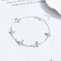 Elegante pulsera de plata de ley 925 con dijes de mariposa y cadena ajustable sobre fondo blanco - Plata 925 / Plateado