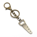 Detail of vintage bronze alloy keychain featuring a mini hand saw tool pendant charm - Saw