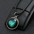 Close-up of a luminous blue heart glass pendant on a black leather display stand - Leo