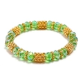 Elastic beaded bracelet featuring emerald green faceted crystal beads and golden metal spacers - Green