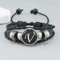 Detail view of multi-layer leather bracelet featuring a black letter V charm and woven cord - Letter V