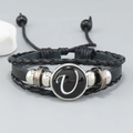 Detail of layered black leather bracelet with letter V bead and metallic accents - Letter U