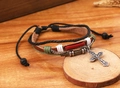 Dettaglio di un bracciale vintage in pelle multistrato con croce d'argento e perle di legno - Marrone