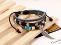 Dettaglio di bracciale in pelle multistrato con ciondolo a piuma d'argento e perline - Nero