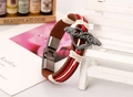 Dettaglio di un bracciale in pelle vintage con ciondolo a cuore alato e cordini - Stile Donna