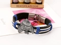 Dettaglio di un bracciale in pelle intrecciata vintage con un ciondolo a pesce in metallo - Stile Uomo