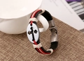 Dettaglio di un bracciale in pelle intrecciata con ciondolo in metallo inciso con croce - Stile Nero Da Donna