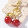 Handmade cherry keychain with red resin glitter fruit and golden metal leaves on stone surface - Gold (Red Cherry)