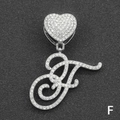 Macro shot of silver letter F pendant with iced-out heart clasp on black display - Letter F / Silver
