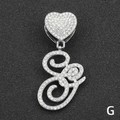 Macro detail of silver iced-out cursive letter G pendant with a sparkling heart clasp - Letter G / Silver