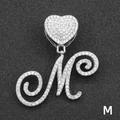 Macro shot of silver letter M pendant with iced-out heart clasp on black texture - Letter M / Silver