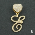 Macro shot of gold-plated letter E pendant with crystal pavé and heart-shaped bail - Letter E / Gold