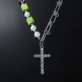 Collar de cruz con cuentas verdes y pedrería sobre fondo negro con reflejo nítido - Collar de Cruz