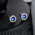Orecchini a perno con zircone blu scuro e alone argentato su sfondo nero lucido - Orecchini Zirconia Blu