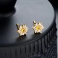 Macro shot of gold snowflake earrings with sparkling zircon stones on a black display stand - Gold (X834-B)