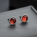 Minimalist red gemstone stud earrings with silver beaded trim on dark display - Red