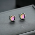 Macro shot of colorful chameleon gemstone studs with silver beaded edges on dark surface - Colorful